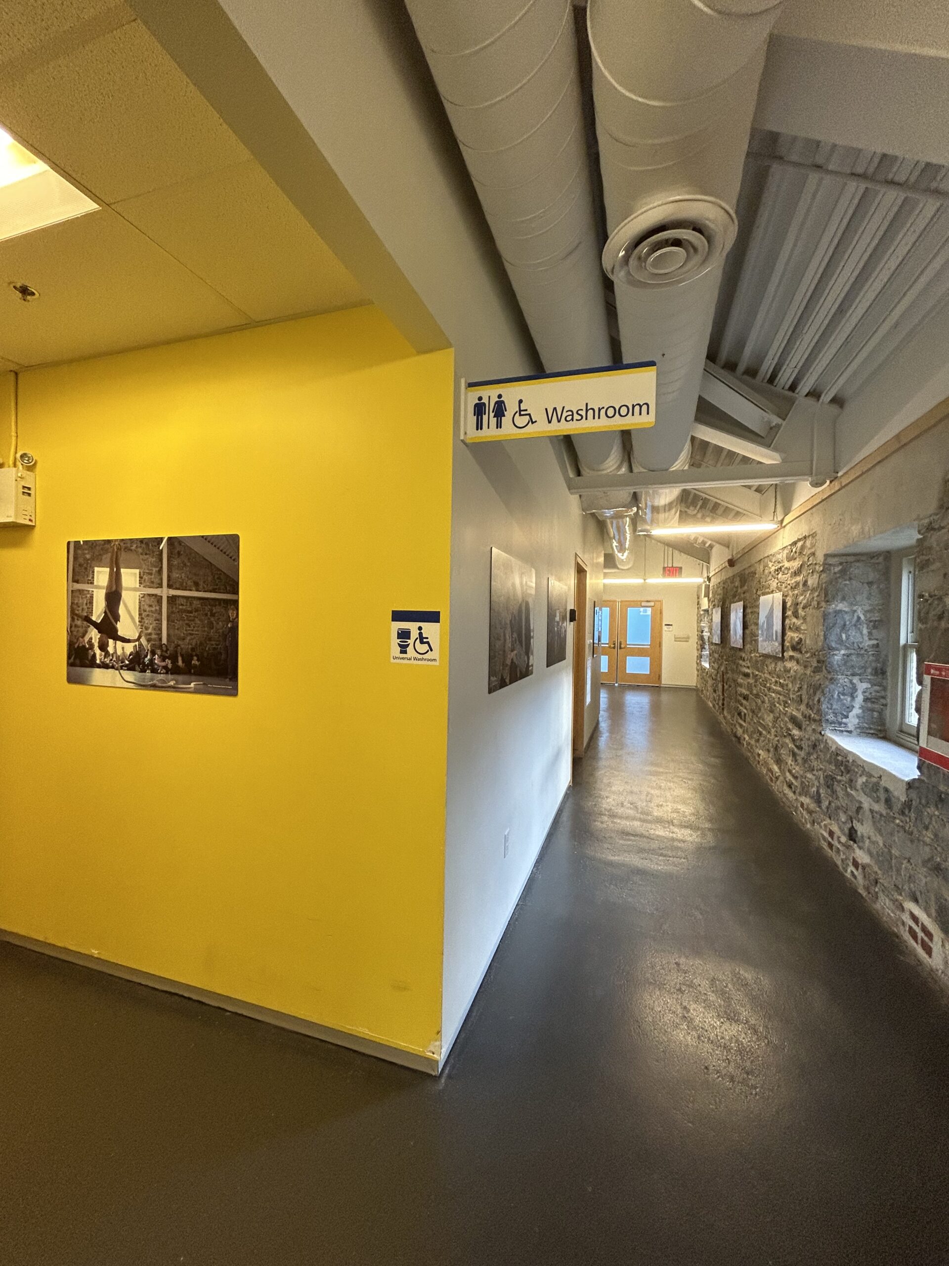 Third Floor hallway [washrooms on the left side with yellow painted walls, limestone walls along the right side, leading to the Malting Tower entrance door at the end of the hallway]